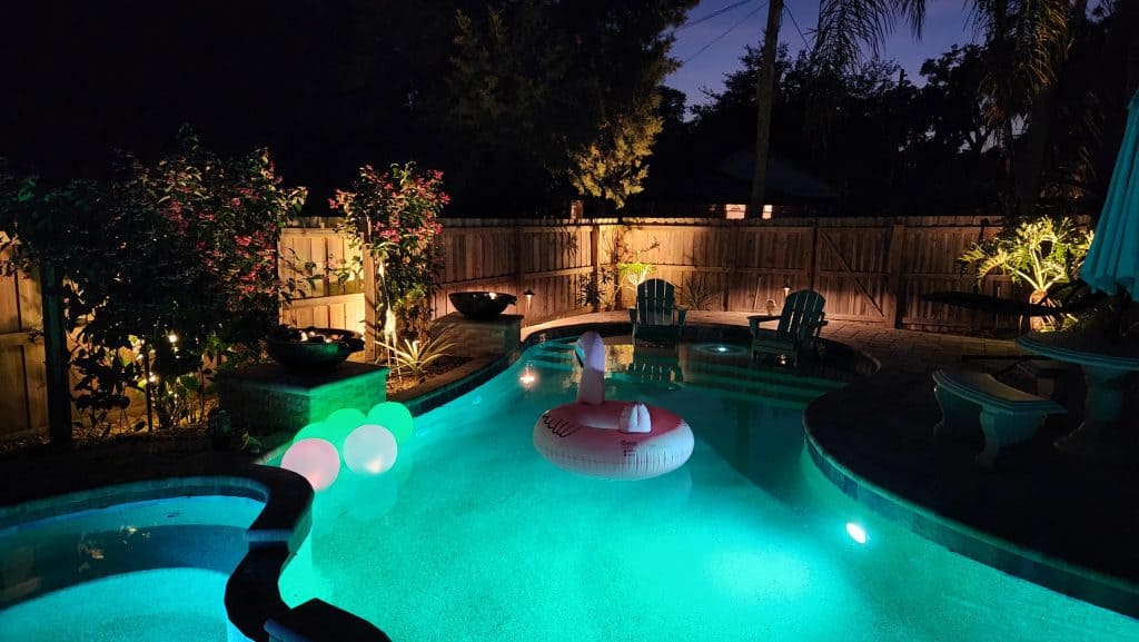 A lit-up backyard pool area. Lightscaped by Atlantic Outdoor Lighting